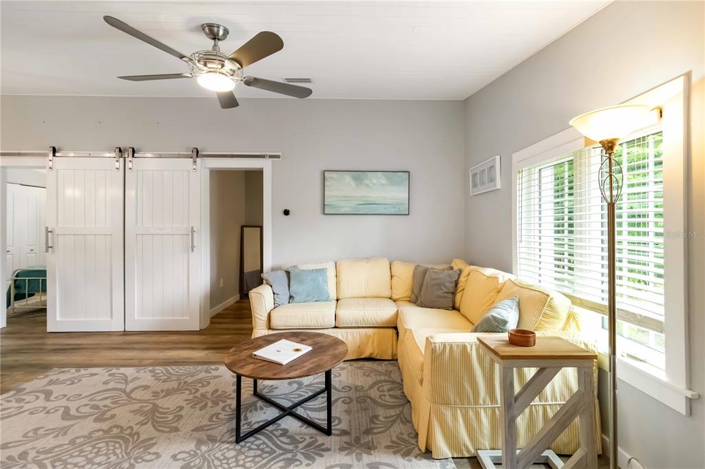A living room features a yellow sectional sofa, a round coffee table, and sliding barn doors — 2537 ASHTON ROAD, SARASOTA, FL