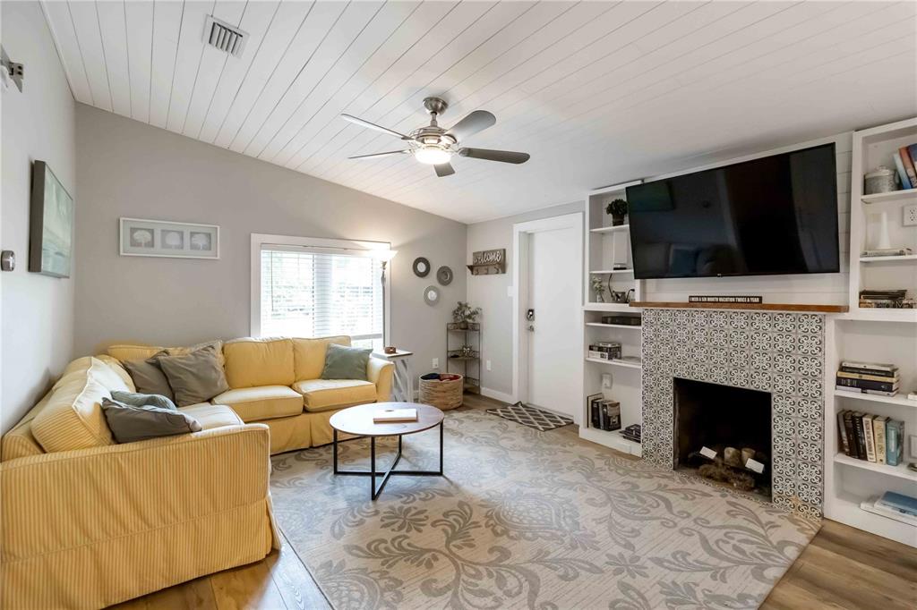 A living room features a yellow sectional sofa, a tiled fireplace, and built-in shelving — 2537 ASHTON ROAD, SARASOTA, FL