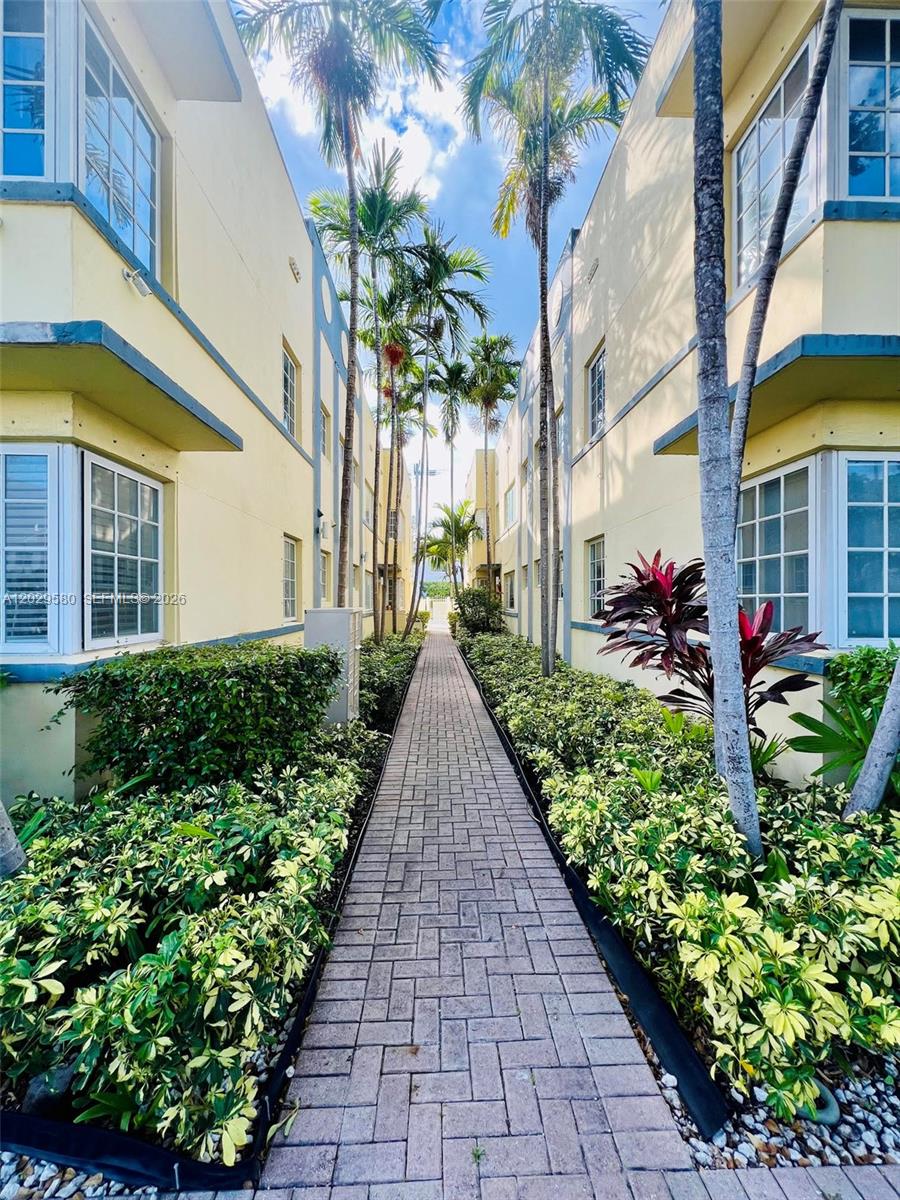 A brick walkway leads between two yellow apartment buildings lined with palm trees and shrubs — 600 Euclid Ave # 5A, Miami Beach FL 33139, MIAMI BEACH, FL
