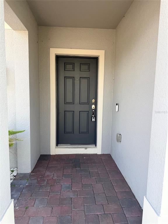 A dark gray six-panel front door is set within a covered entryway with brick pavers — 269 HAMLET LOOP, DAVENPORT, FL