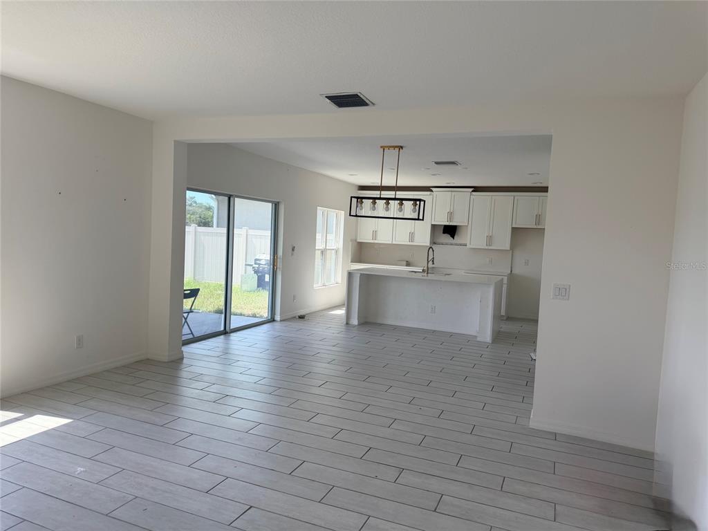 An open-concept kitchen and living area features white cabinetry, a center island, and tile flooring — 269 HAMLET LOOP, DAVENPORT, FL