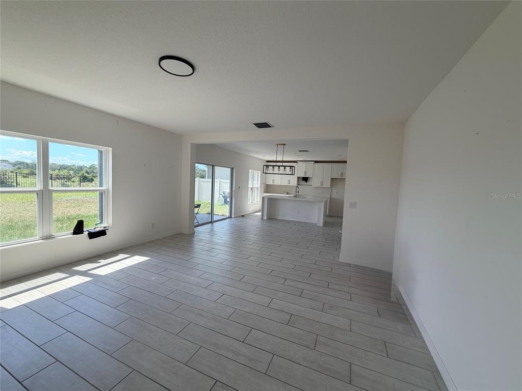 An open-concept living area features light-colored tile flooring, white walls, and a kitchen island — 269 HAMLET LOOP, DAVENPORT, FL