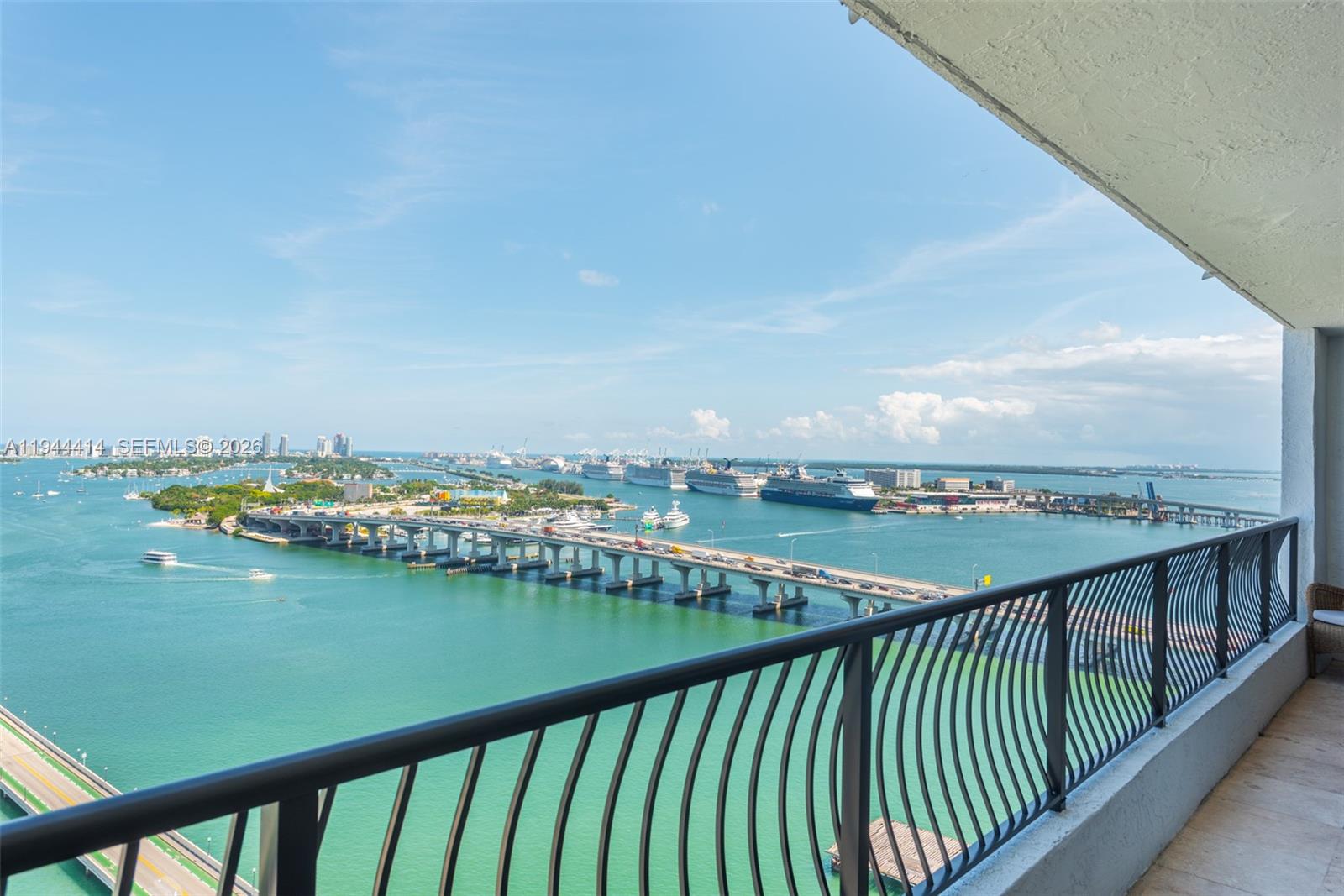 A high-angle view from a balcony overlooks a bridge, cruise ships, and the ocean — 555 NE 15th St # 26B, Miami FL 33132, MIAMI, FL