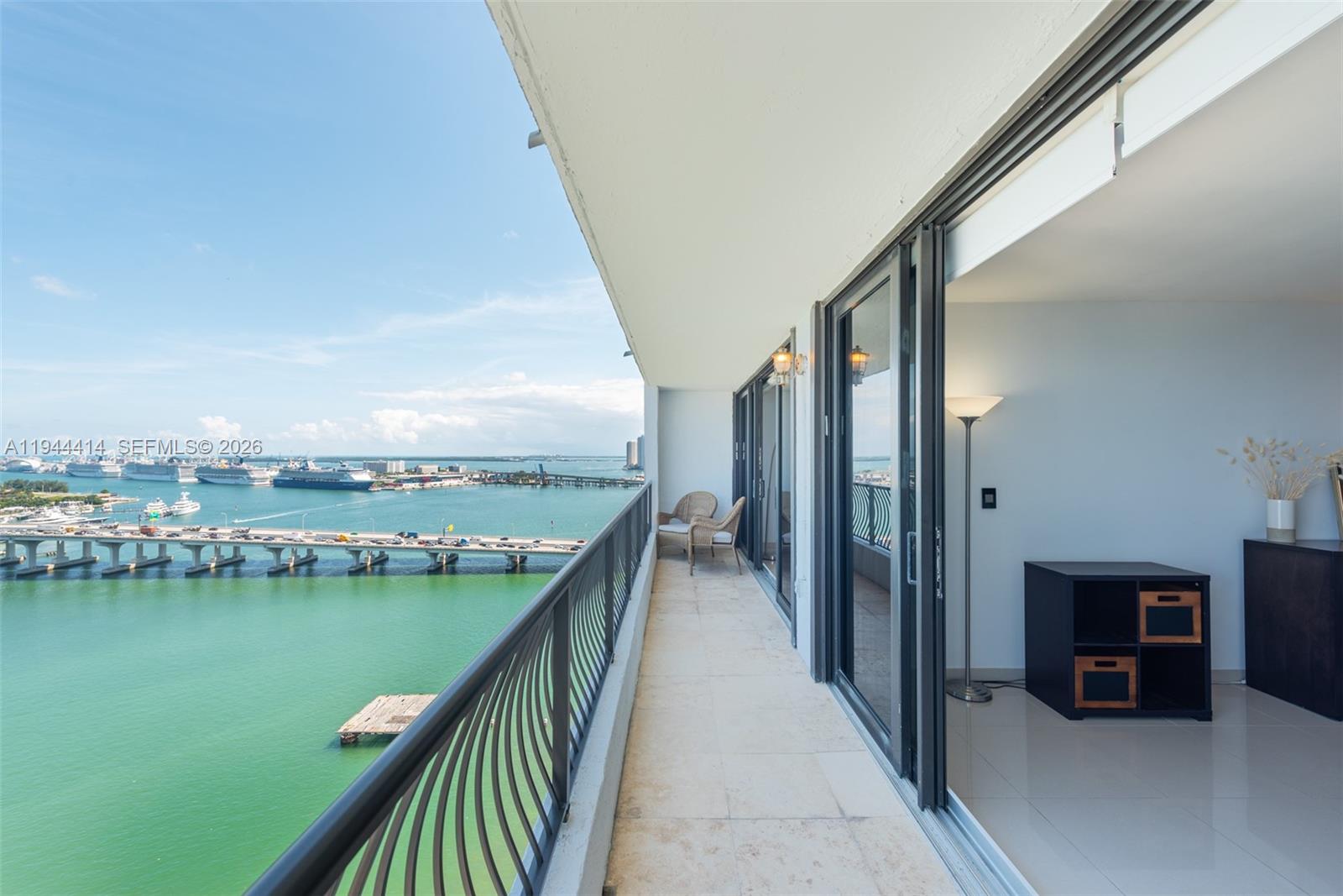 A balcony with tile flooring overlooks a bay, a bridge, and cruise ships — 555 NE 15th St # 26B, Miami FL 33132, MIAMI, FL