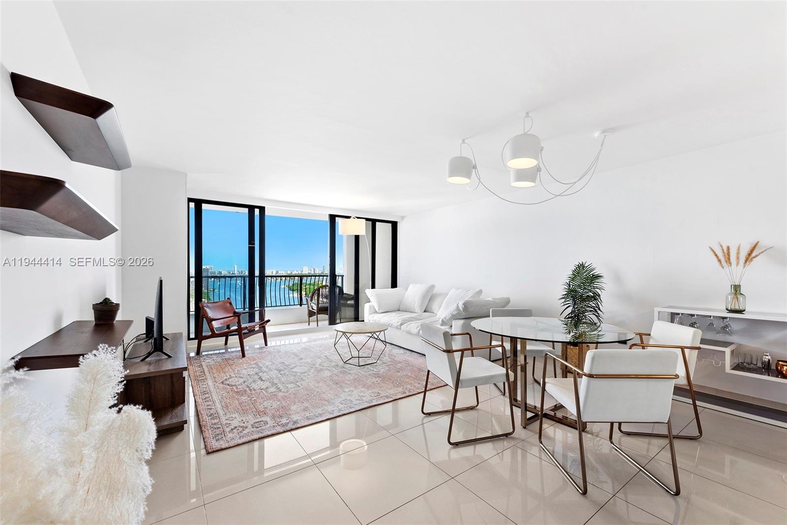 A bright living and dining area features tile floors, modern furniture, and a balcony view — 555 NE 15th St # 26B, Miami FL 33132, MIAMI, FL