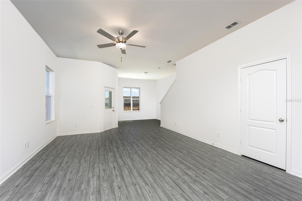 An empty room with white walls, gray wood-look flooring, a ceiling fan, and two doors — 643 POPPY LANE, DUNDEE, FL