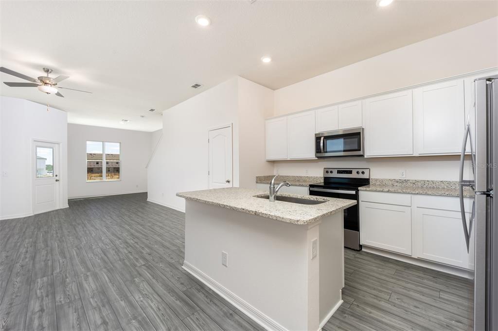 A kitchen with white cabinets, granite countertops, and an island overlooks an open living area — 643 POPPY LANE, DUNDEE, FL