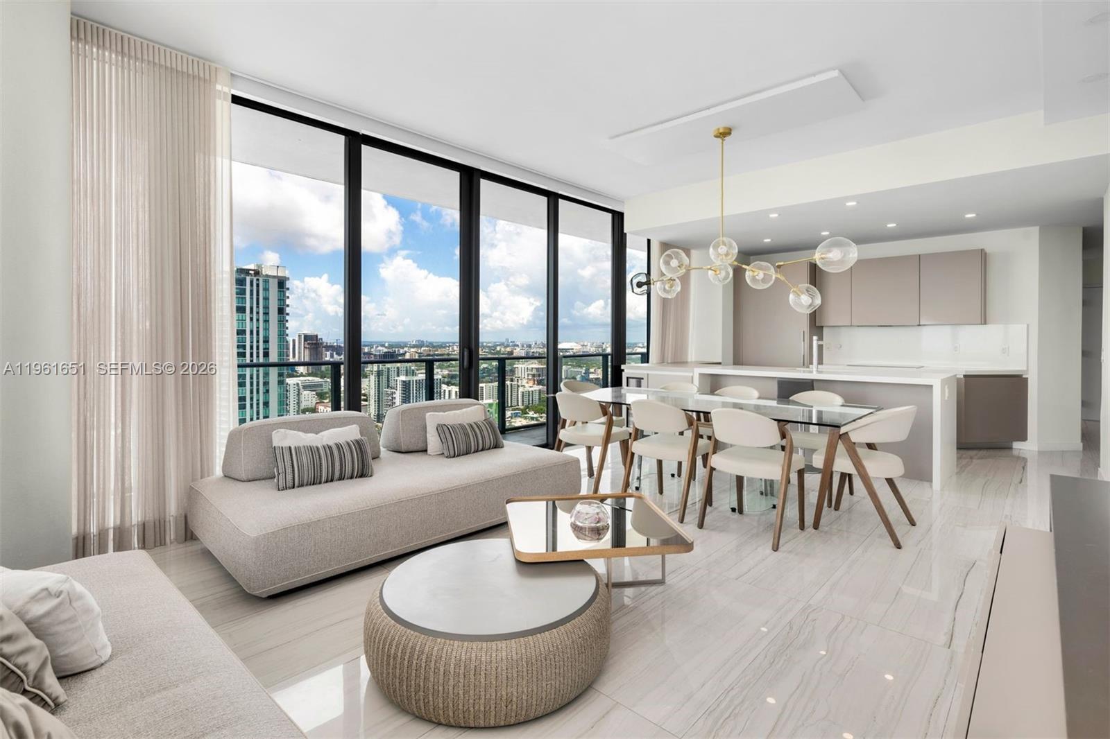 A modern open-concept living and dining area features floor-to-ceiling windows with a city view — 480 NE 31st St # 3401, Miami FL 33137, MIAMI, FL