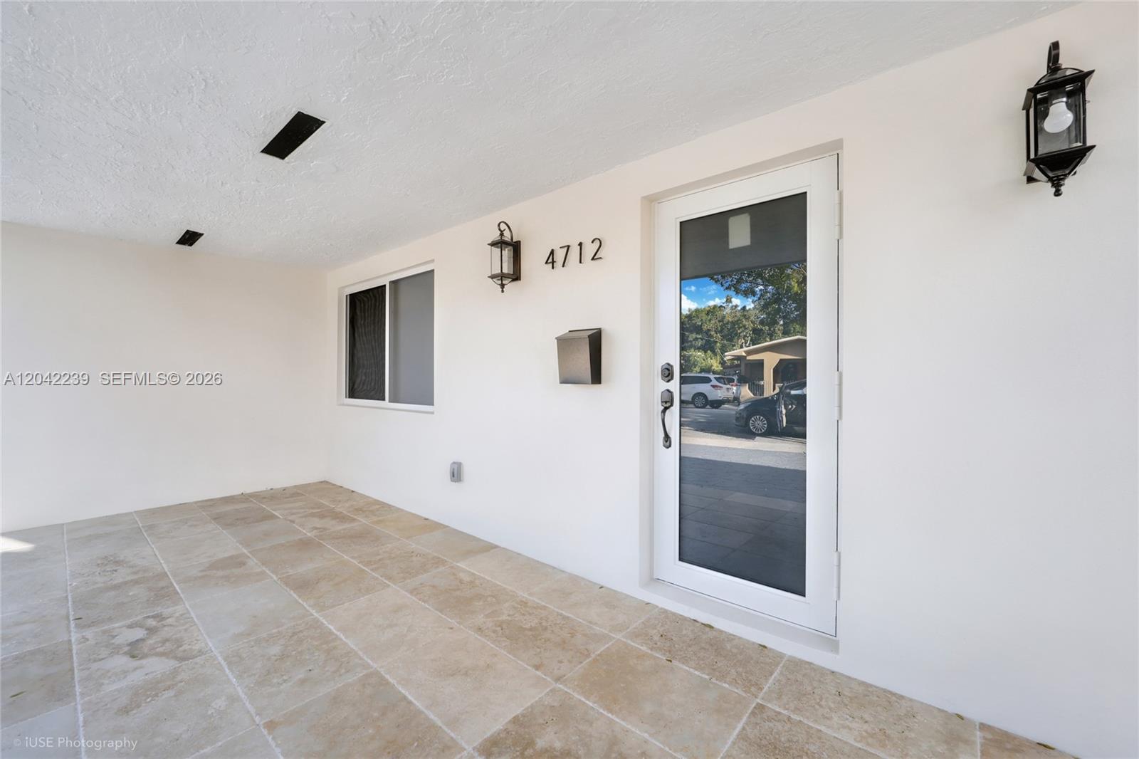 A white exterior wall features a front door, a window, and two wall-mounted lanterns — 4712 SW 2nd Ter, Miami FL 33134, MIAMI, FL