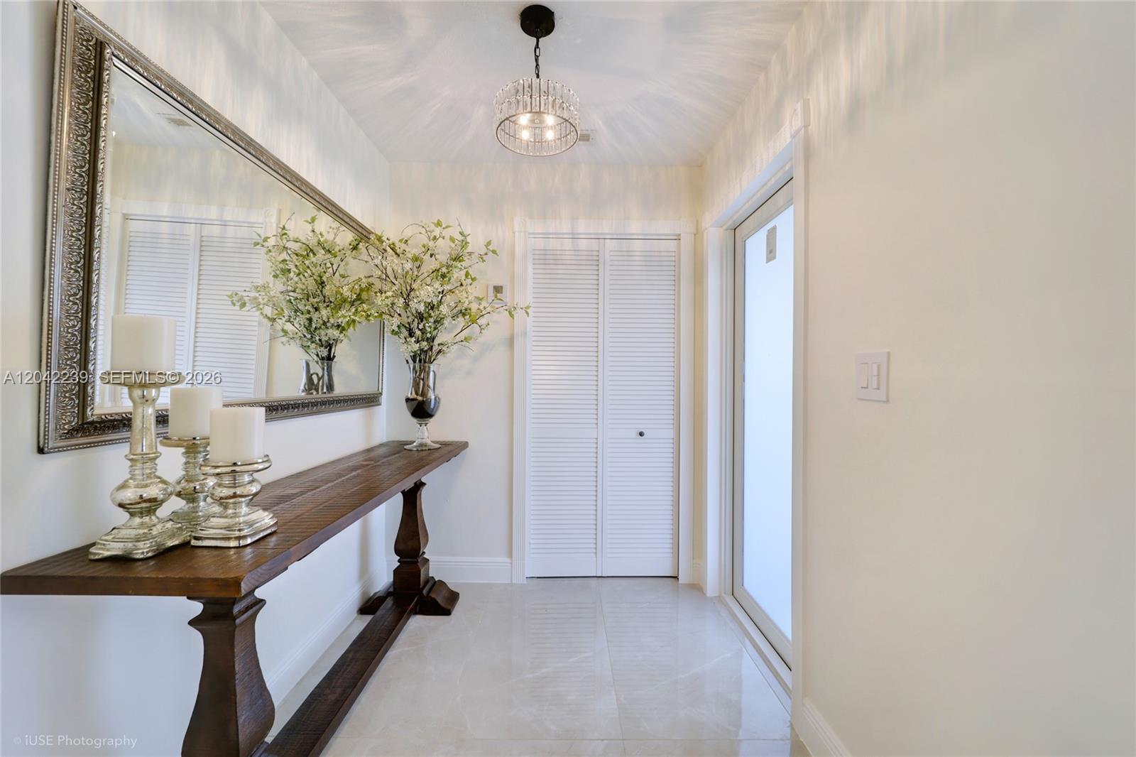 A bright entryway features a wooden console table, a large mirror, and a crystal chandelier — 4712 SW 2nd Ter, Miami FL 33134, MIAMI, FL