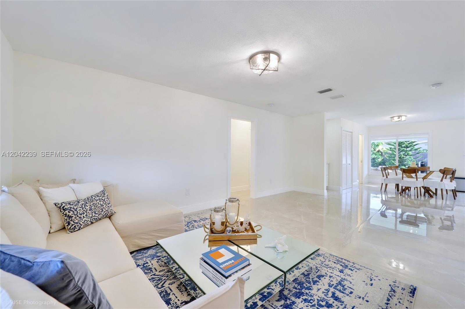 A living room with a white sectional sofa, glass coffee table, and dining area beyond — 4712 SW 2nd Ter, Miami FL 33134, MIAMI, FL