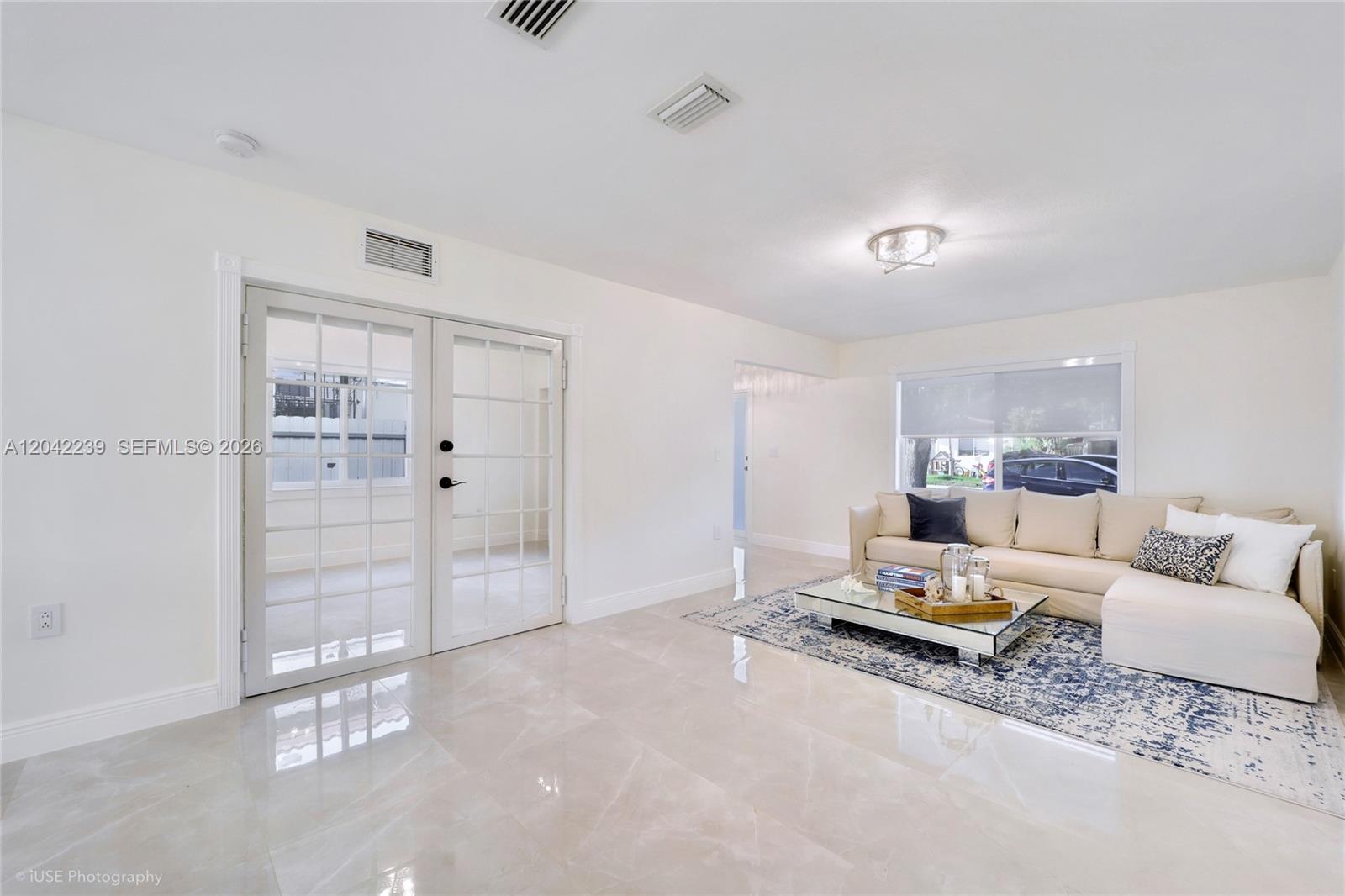 A living room features light tile floors, a beige sectional sofa, and glass French doors — 4712 SW 2nd Ter, Miami FL 33134, MIAMI, FL