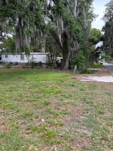 A mobile home sits on a grassy lot shaded by large, moss-covered oak trees — 3799 AVENUE T NW, WINTER HAVEN, FL