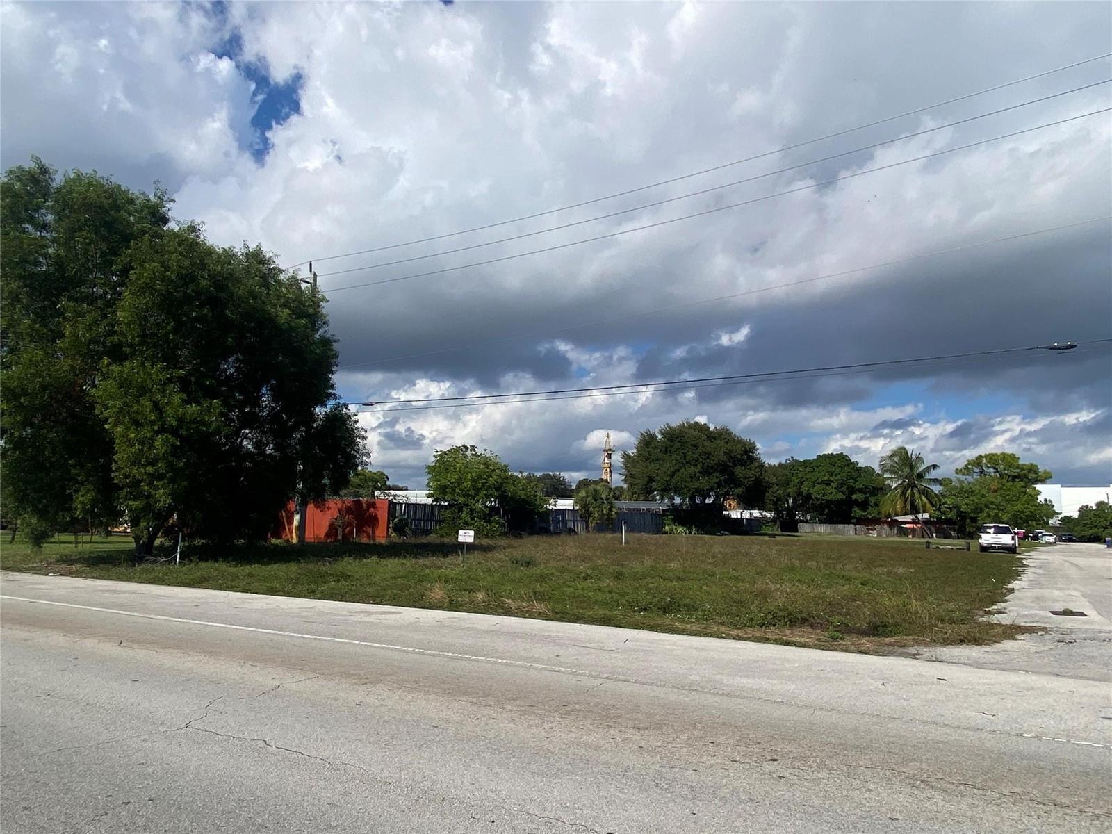 A vacant, grassy lot sits beside a paved road under a cloudy sky — Nw 19 NW 19th Avenue, Pompano Beach FL 33069, POMPANO BEACH, FL