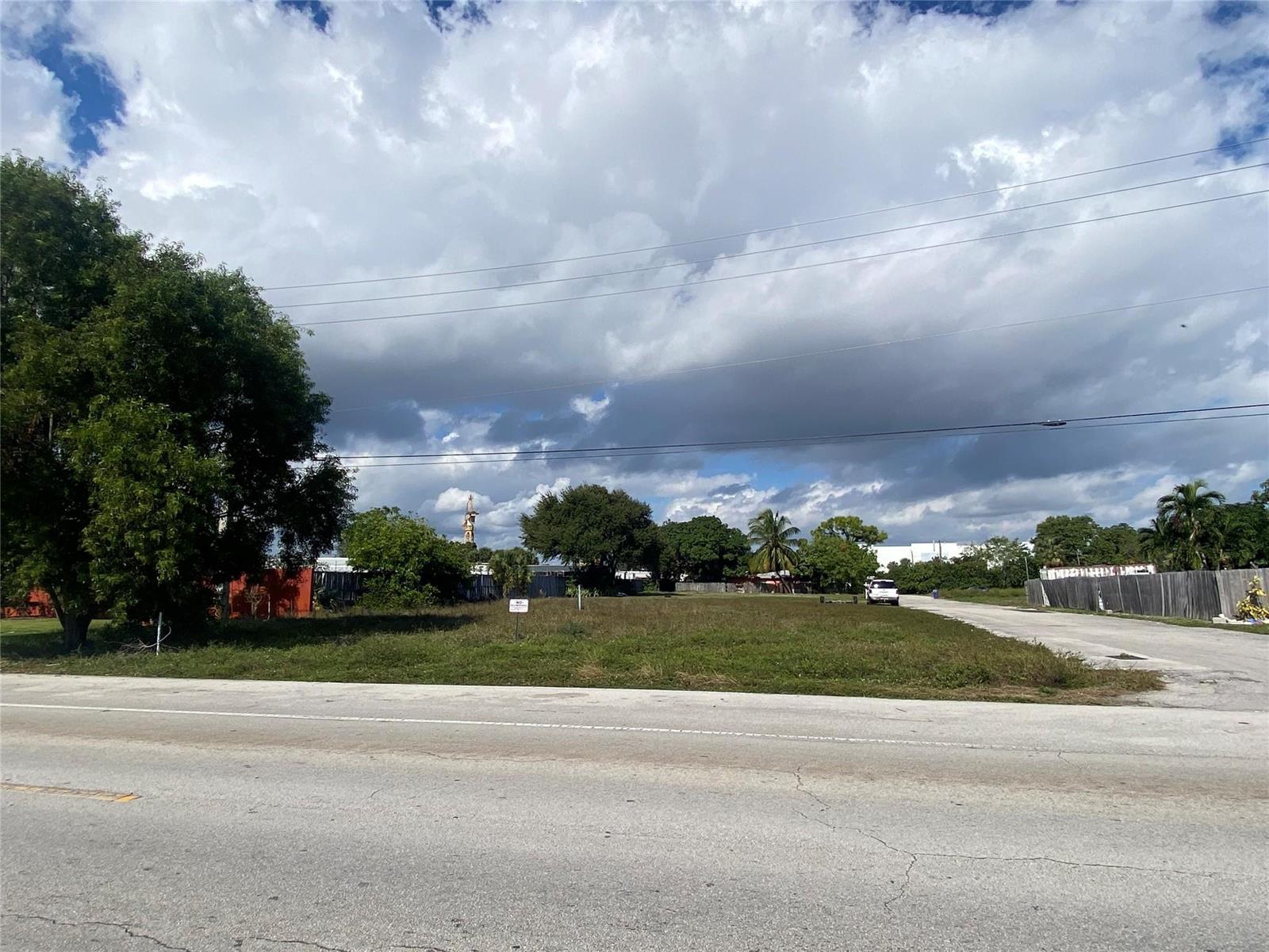 A vacant, grassy lot sits beside a paved road under a cloudy sky — Nw 19 NW 19th Avenue, Pompano Beach FL 33069, POMPANO BEACH, FL