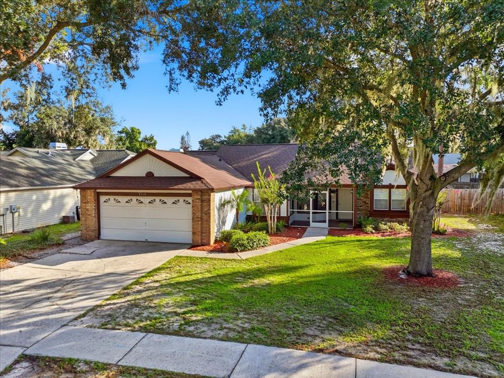 A single-story house with a two-car garage, a screened front porch, and large oak trees — 4110 LONGFELLOW DRIVE, PLANT CITY, FL