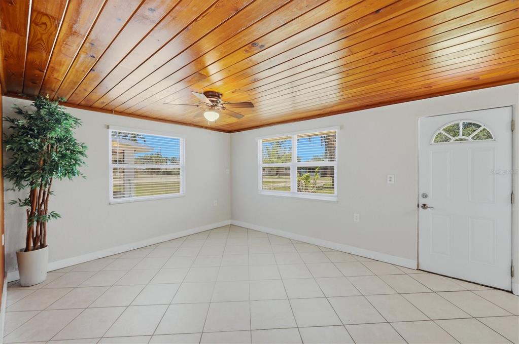 A room with light tile flooring, a wood-paneled ceiling, and a white front door — 155 MAGNOLIA AVENUE, ENGLEWOOD, FL