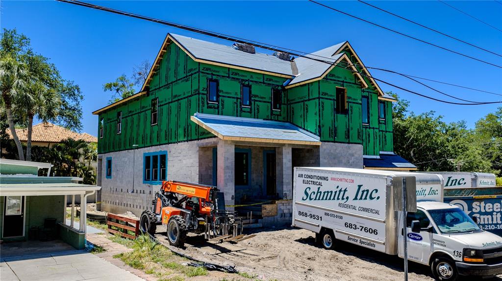 A two-story house under construction features green sheathing, concrete block walls, and a construction vehicle — 4316 W CORONA STREET, TAMPA, FL