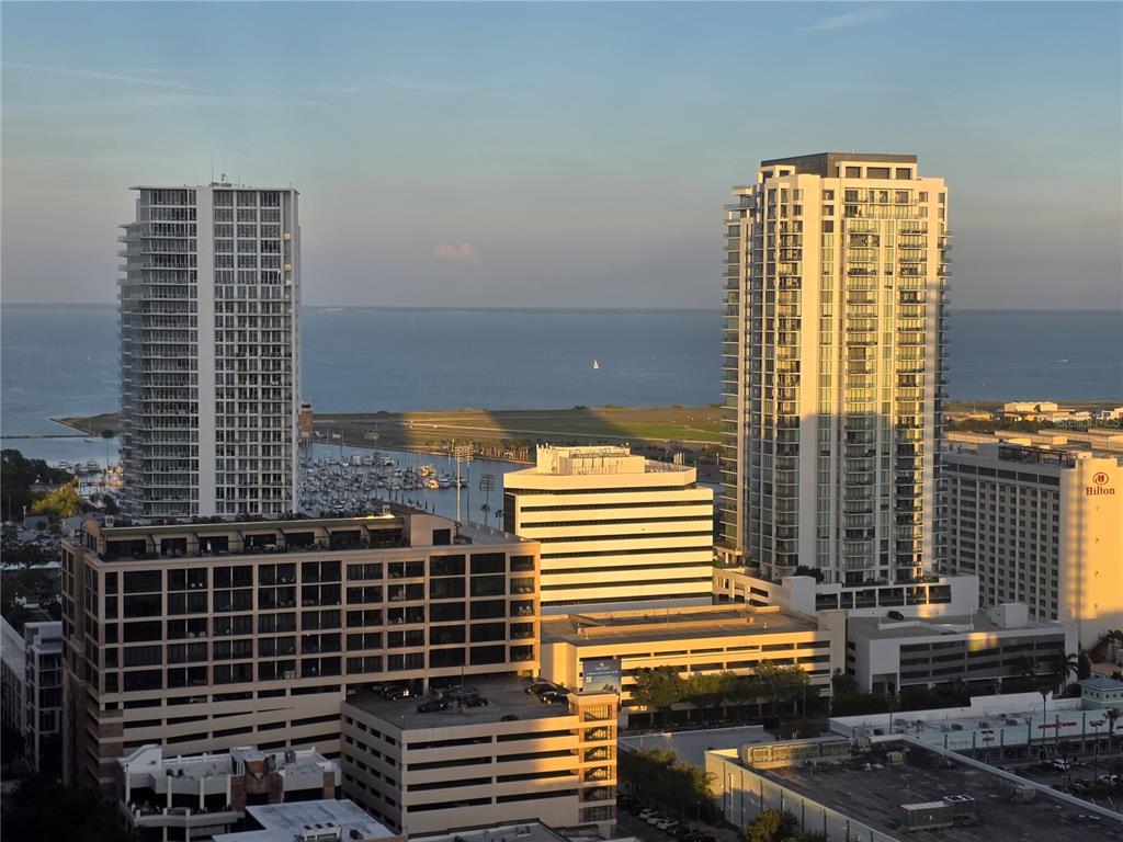 A furnished balcony with a city and water view overlooks a street with tall buildings — 400 CENTRAL AVENUE UNIT 2505, ST PETERSBURG, FL