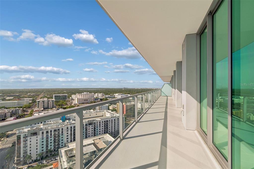 A high-rise balcony features outdoor seating, potted plants, and a dining table overlooking a city — 400 CENTRAL AVENUE UNIT 2505, ST PETERSBURG, FL