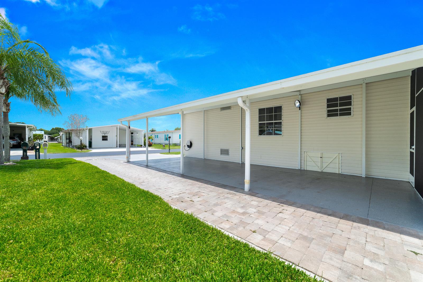 A paved driveway leads to a covered carport beside a light-colored mobile home — 1637 SW 35th Circle, Okeechobee FL 34974, OKEECHOBEE, FL