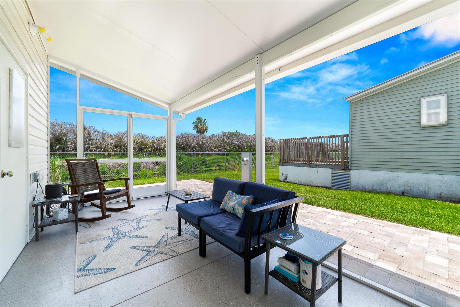 A screened-in patio features a blue sofa, a rocking chair, and a paved outdoor area — 1637 SW 35th Circle, Okeechobee FL 34974, OKEECHOBEE, FL