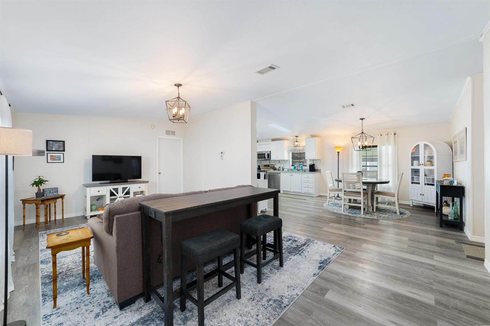 An open-concept living and dining area features light wood flooring, white cabinetry, and neutral walls — 1637 SW 35th Circle, Okeechobee FL 34974, OKEECHOBEE, FL