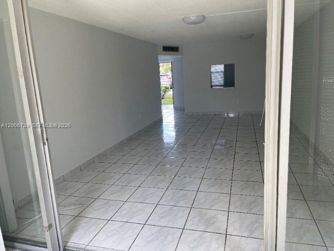 An empty room with light-colored tile flooring and a view through a doorway — 1701 NE 191st St # A106, Miami FL 33179, MIAMI, FL