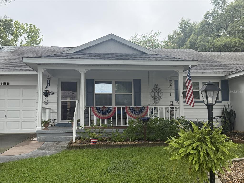 A single-story house features a covered front porch with patriotic bunting and a lawn — 8658 SW 95TH LANE UNIT B, OCALA, FL
