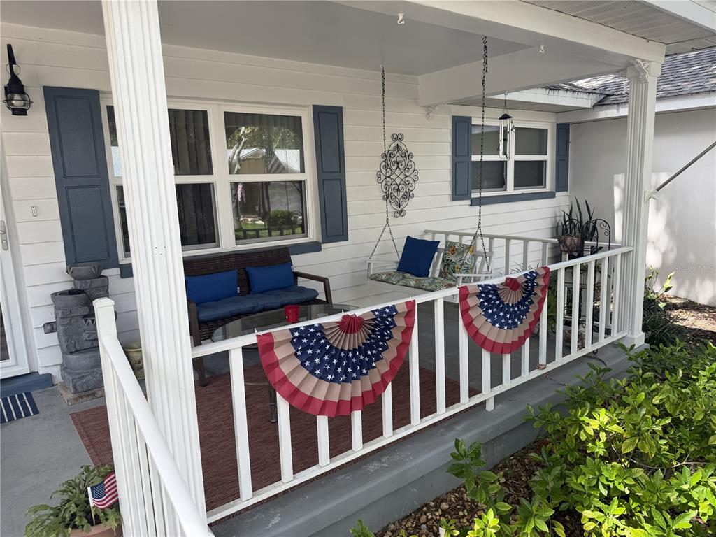 A covered front porch features a white railing, a hanging swing, and patriotic bunting decorations — 8658 SW 95TH LANE UNIT B, OCALA, FL