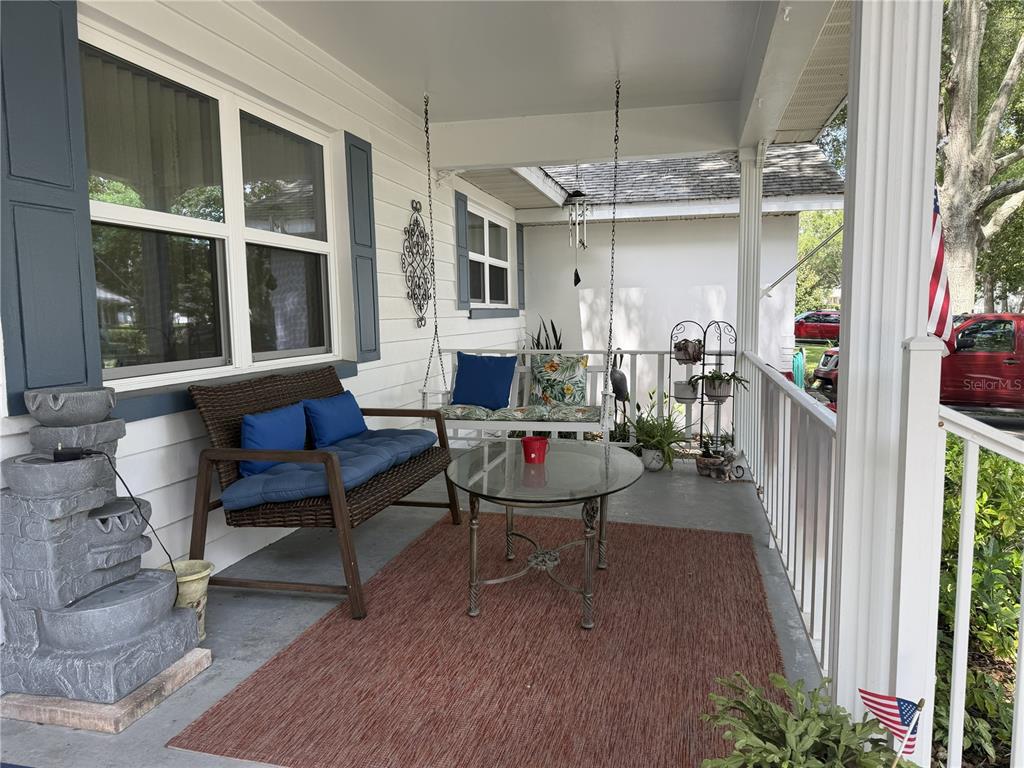 A covered front porch features a wicker bench, a hanging swing, and a glass-topped table — 8658 SW 95TH LANE UNIT B, OCALA, FL