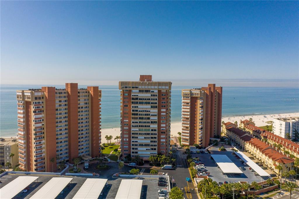 An aerial view shows three tall residential buildings situated along a sandy beach — 17920 GULF BOULEVARD UNIT 2006, REDINGTON SHORES, FL