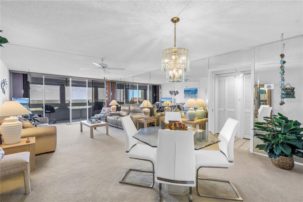 A dining area and living room with mirrored walls, a glass table, and balcony views — 17920 GULF BOULEVARD UNIT 2006, REDINGTON SHORES, FL