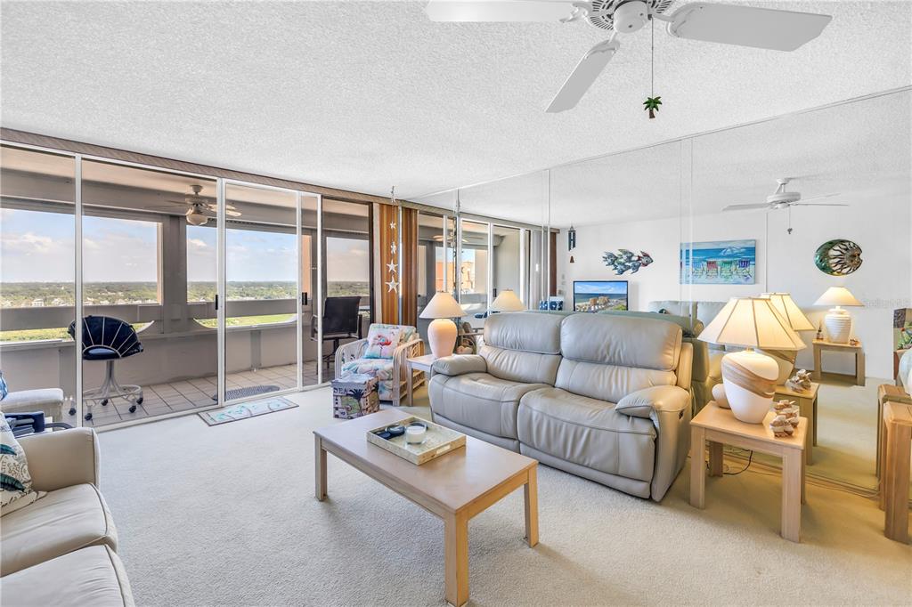 A living room features a beige sofa, coffee table, mirrored wall, and a balcony view — 17920 GULF BOULEVARD UNIT 2006, REDINGTON SHORES, FL