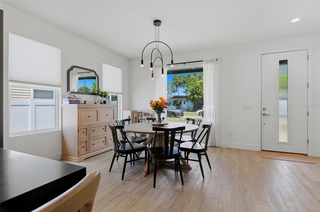 A dining room features a round wooden table, black chairs, and a modern light fixture — 5160 DARTMOUTH AVENUE N, ST PETERSBURG, FL