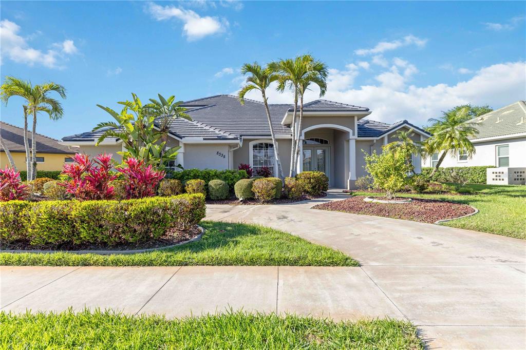 A single-story house with a tiled roof, palm trees, and a concrete driveway — 8335 BARTON FARMS BOULEVARD, SARASOTA, FL