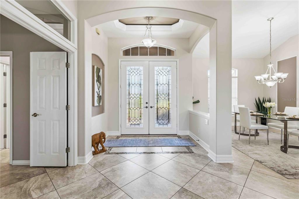 A tiled entryway features double glass-paneled doors, an arched ceiling, and an adjacent dining area — 8335 BARTON FARMS BOULEVARD, SARASOTA, FL