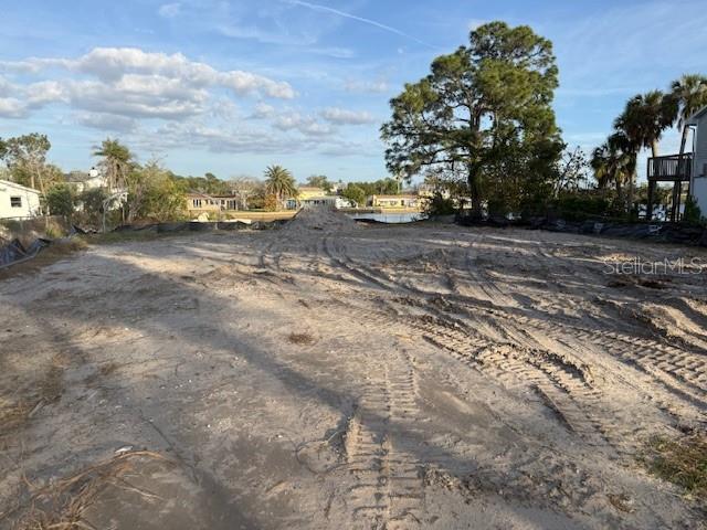 A vacant, sandy lot with tire tracks leads toward a waterfront view and distant houses — 5250 MILLER BAYOU DRIVE, PORT RICHEY, FL