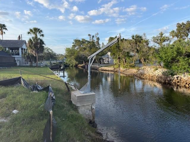A metal boat lift stands on a concrete base along a canal next to a yard — 5250 MILLER BAYOU DRIVE, PORT RICHEY, FL