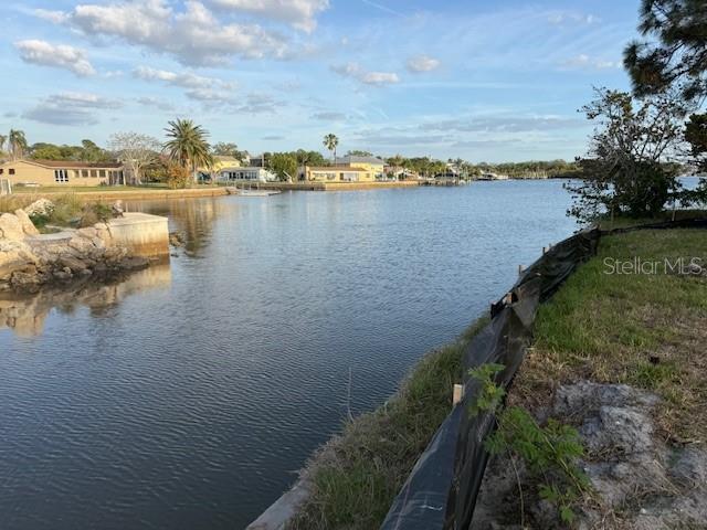 A view of a canal with houses, palm trees, and a silt fence in foreground — 5250 MILLER BAYOU DRIVE, PORT RICHEY, FL