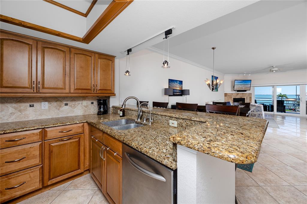 A kitchen with wood cabinets and granite countertops overlooks an open-concept living area with ocean views — 363 PINELLAS BAYWAY S UNIT 48, TIERRA VERDE, FL
