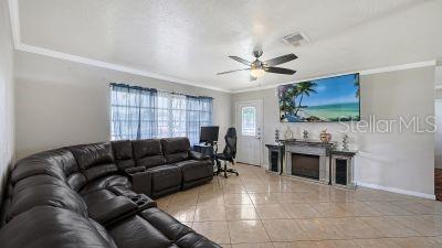 A living room features a large leather sectional, a ceiling fan, and a fireplace — 1104 FRUITLAND AVE., BRADENTON, FL