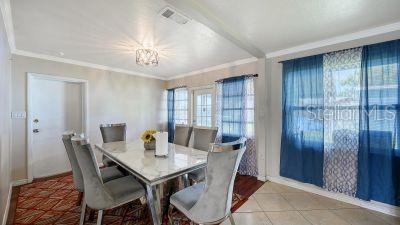 A dining room features a marble-topped table, six gray upholstered chairs, and blue curtains — 1104 FRUITLAND AVE., BRADENTON, FL