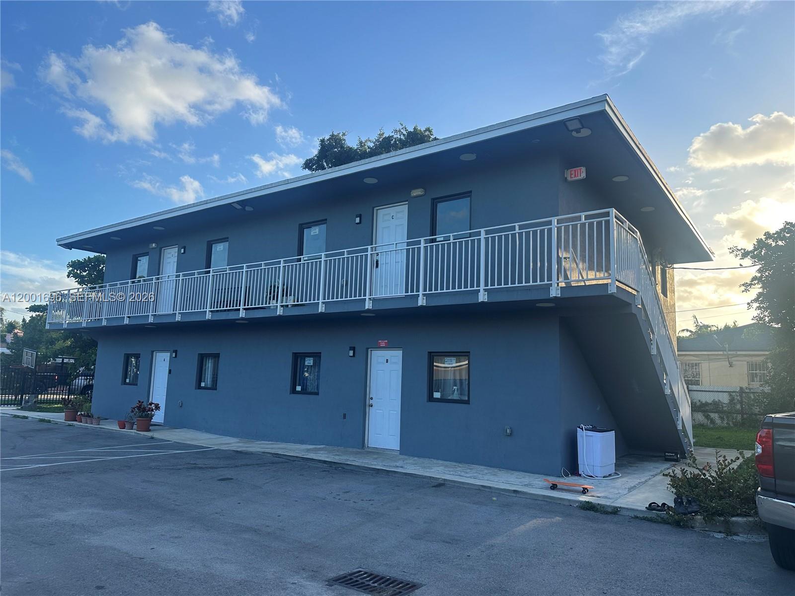 A two-story blue apartment building features exterior staircases, white railings, and multiple entry doors — 587 NW 100th St # C, Miami FL 33150, MIAMI, FL