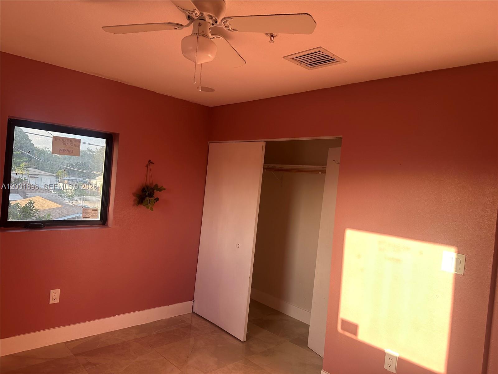 A bedroom with pink walls, tile flooring, a ceiling fan, and an open closet — 587 NW 100th St # C, Miami FL 33150, MIAMI, FL