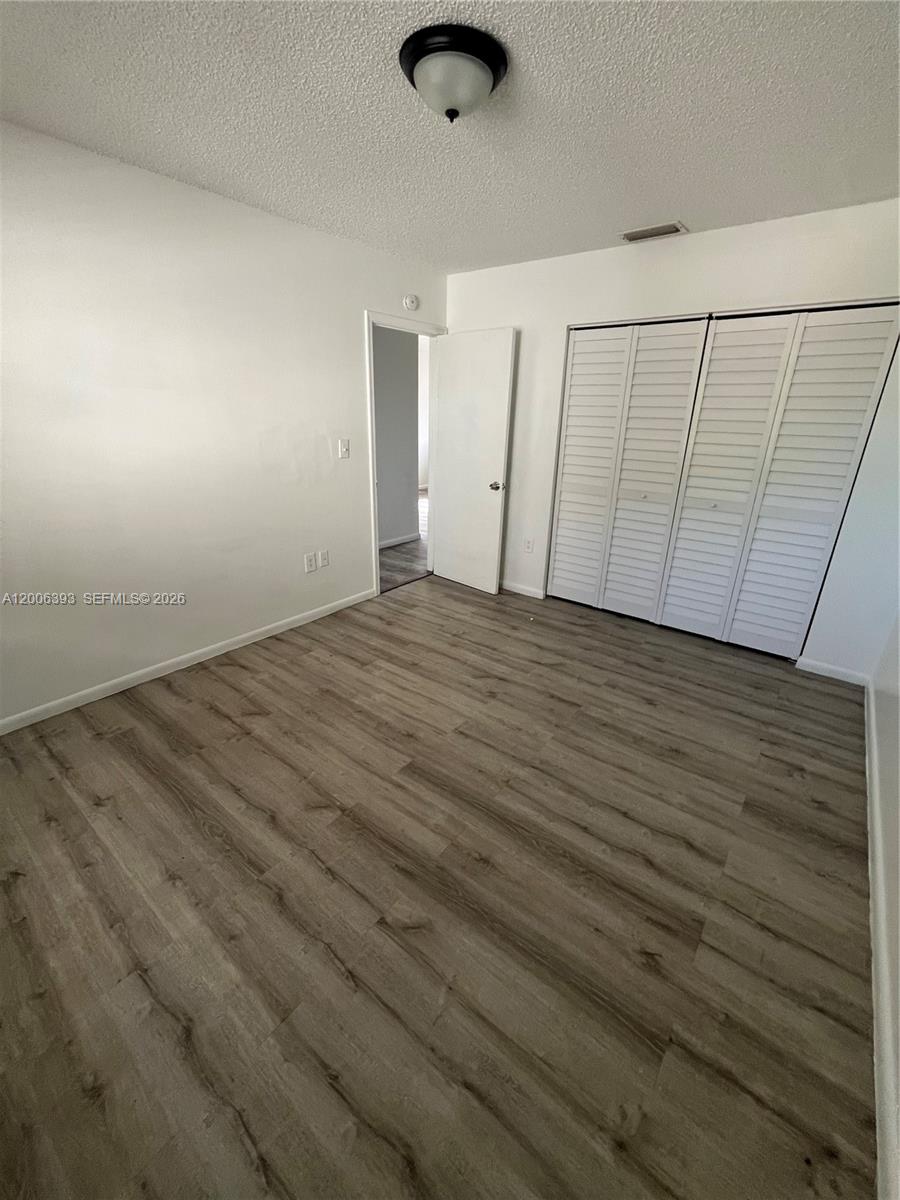 An empty bedroom features white walls, a louvered closet, and light-colored wood-look flooring — 334 E 21st St # 3, Hialeah FL 33010, HIALEAH, FL