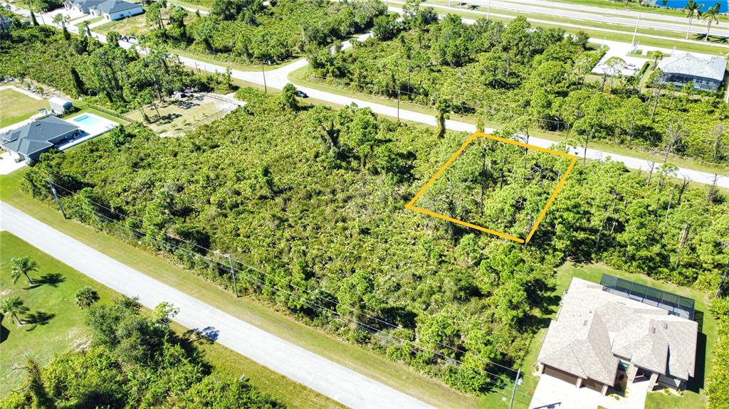 An aerial view shows a vacant, wooded residential lot outlined in yellow near a road — 8178 DIMSTEAD STREET, PORT CHARLOTTE, FL