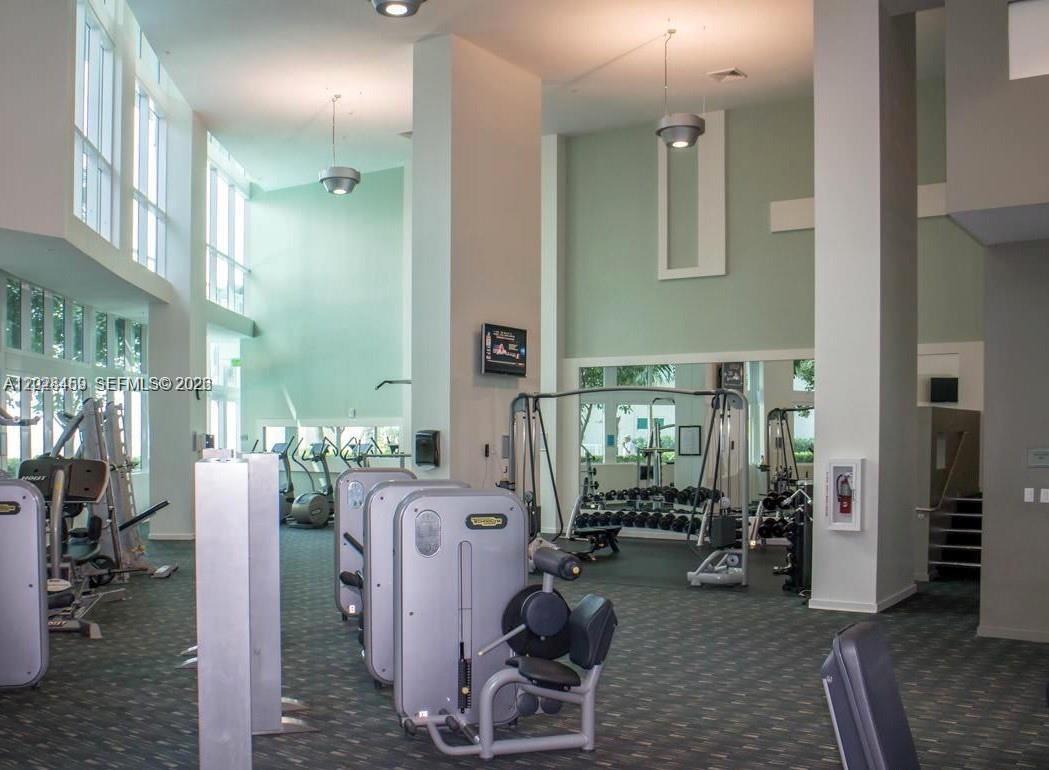A gym with various exercise machines, large windows, and a mirrored wall — 1900 N Bayshore Dr # 2415, Miami FL 33132, MIAMI, FL