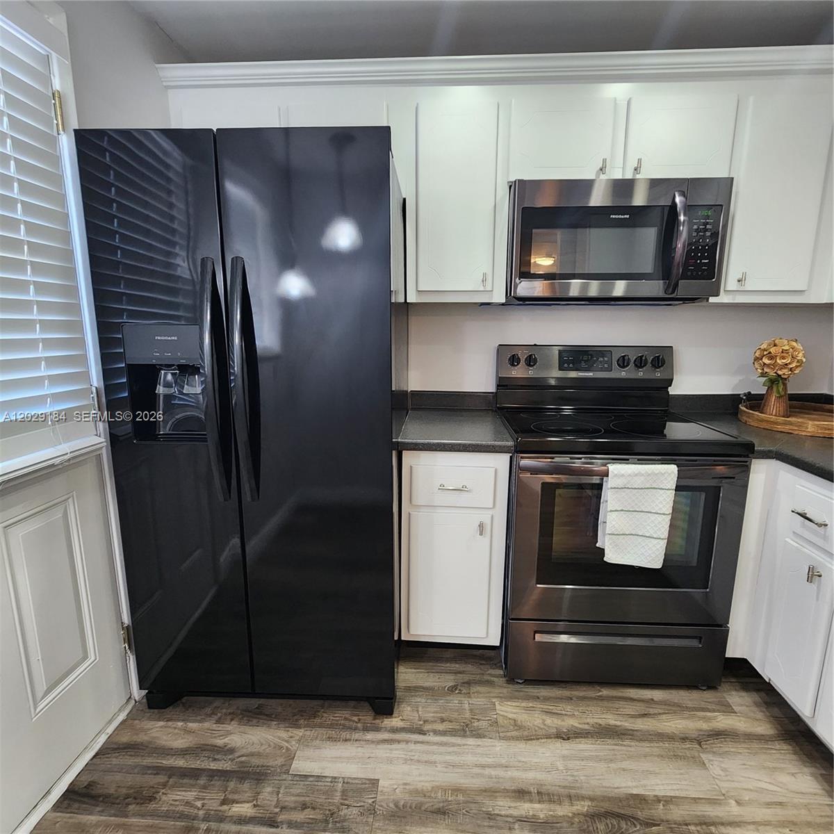 A kitchen features white cabinets, a black refrigerator, and stainless steel appliances — 900 NE 12th Ave # 406, Hallandale Beach FL 33009, HALLANDALE BEACH, FL