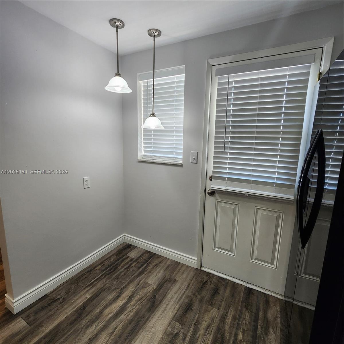 A small room features wood-look flooring, two pendant lights, a window, and a door — 900 NE 12th Ave # 406, Hallandale Beach FL 33009, HALLANDALE BEACH, FL
